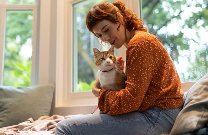 Woman in orange sweater holding cat